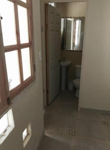 a hallway of a bathroom with a toilet and a window at Hostal CacTus in Coquimbo