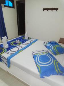 una cama con mantas y almohadas azules y blancas en Hotel Villa Luna del Llano, en Villavicencio
