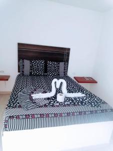 Una cama con un edredón blanco y negro. en Hotel Villa Luna del Llano, en Villavicencio 3 fotos más