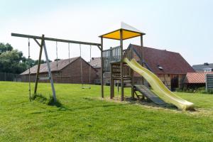 un parque infantil con un tobogán en el césped en Apartment 't Maanhof, en Gingelom