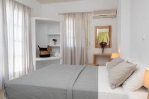 a white bedroom with a large bed and a window at Vavoulas Village in Mikri Vigla