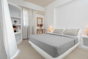 een witte slaapkamer met een bed en een raam bij Vavoulas Village in Mikri Vigla