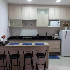 a kitchen with a counter with four chairs around it at Residencial Flats Botanicus 1 in Olímpia