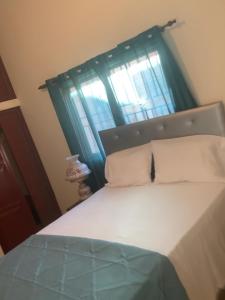 a bedroom with a bed with a window with blue curtains at Marbella1 in Los Frailes