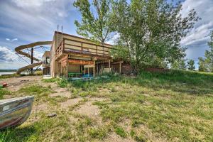 a house on a hill with a boat in front of it at Lakefront Country Home with Waterslide and Trampoline! in Wheatland