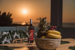 a table with a basket of fruit and a bottle of wine at Villa VerdeBlu Rethymno Crete in Rethymno Town