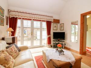 a living room with a couch and a tv at The Coach House in Duns