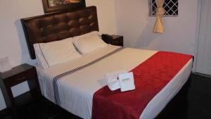 una camera da letto con un grande letto con una coperta rossa di Casa Hotel Victoria a Bogotá
