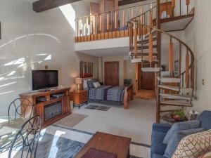 a living room with a couch and a television and a staircase at Tamarron Lodge Loft 314 in Durango