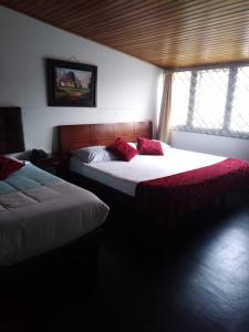 a bedroom with two beds with red pillows on them at Casa Hotel Victoria in Bogotá