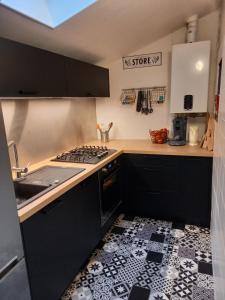 een keuken met zwarte kasten en een zwart-witte tegelvloer bij Gîte 8 places à Fécamp La Bonne Escale in Fécamp
