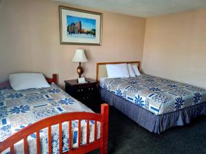 a hotel room with two beds and a table with a lamp at Regal Inn Hampton Beach in Hampton
