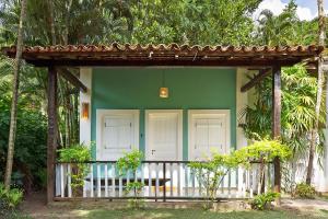 a green house with white doors and a porch at Vila Siriúba Hotel in Ilhabela