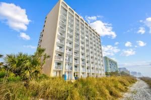 a tall building on the beach next to a beach at Driftwood 51009 in Myrtle Beach