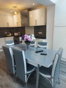 une table à manger avec des chaises et un vase de fleurs. dans l'établissement Modern Comfort House On Eamont RD, à Stockton-on-Tees