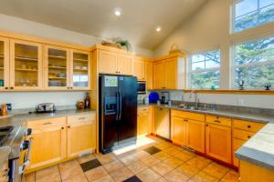 a kitchen with wooden cabinets and a black refrigerator at Twin Rocks Haven in Rockaway Beach +25 photos