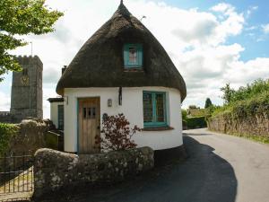 a small house with a thatched roof on a street at The Old Forge in Newton Abbot