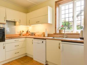 uma cozinha com armários brancos e um lavatório em The Old Forge em Newton Abbot
