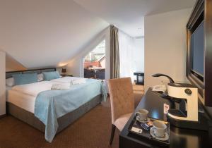 ブダペストにあるバスティオン ホテル ブダペストのベッド、デスク、電話が備わるホテルルームです。