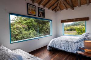 a bedroom with two beds and a large window at Casa Mediterránea Villa de Leyva in Villa de Leyva