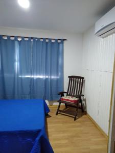 a bedroom with a chair and a blue curtain at El Jacal de San Pedro in San Pedro
