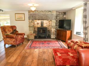 a living room with a stone fireplace and a tv at Plas Mawr in Caernarfon