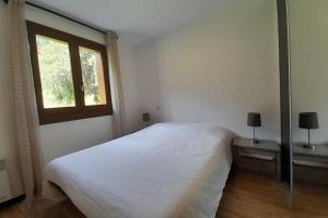 1 dormitorio con cama blanca y ventana en Apartment on the slopes, en La Clusaz
