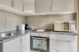 昂蒂布的住宿－Studio Rostagne - Welkeys，厨房配有白色橱柜、微波炉和水槽。
