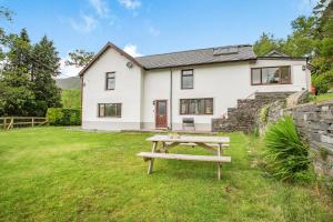 a white house with a picnic table in front of it at Stiniog Lodge in Blaenau-Ffestiniog