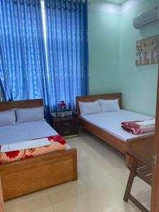 2 camas en una habitación con cortinas azules en MINH THU MOTEL, en An Bình (1)