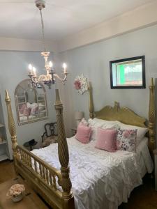 Schlafzimmer mit einem Bett mit rosa Kissen und einem Kronleuchter in der Unterkunft The Suites & Vintage Apartment at Casa Of Essence in heart of Old San Juan in San Juan