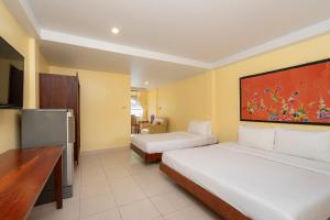 a hotel room with two beds and a desk at Sawasdee Place in North Pattaya