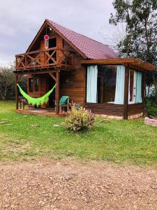 a wooden house with a green ribbon in front of it at Chalé Recanto Verde dos Canyons in Praia Grande