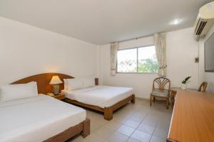 a bedroom with two beds and a table and a chair at Sawasdee Place in North Pattaya