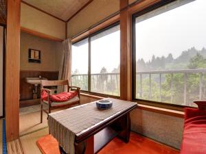 Cette chambre comprend une table, une chaise et des fenêtres. dans l'établissement Setoguchi, à Tōkamachi