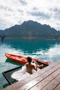 a man sitting on a bench in front of a body of water at Panvaree Resort in Ban Chieo Ko
