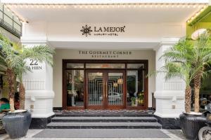 ハノイにあるLa Mejor Hotel & Sky Barのヤシの木が前に立つ建物の玄関