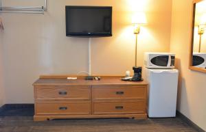 a room with a dresser with a microwave and a tv at Bracebridge Inn in Bracebridge