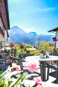 a table and chairs on a patio with mountains in the background at Ferienwohnungen Germania in Schönau am Königssee