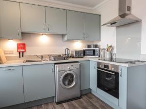 a kitchen with white cabinets and a washer and dryer at The Nook in Inverness