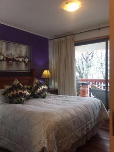 a bedroom with a large bed and a large window at DEPARTAMENTOS TERMAS DE CHILLAN in Nevados de Chillan