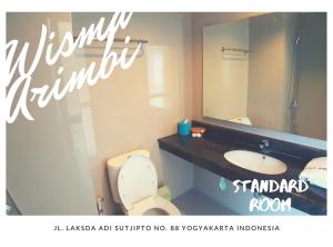 a bathroom with a sink and a toilet and a mirror at Wanitatama Villas in Demangan