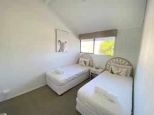 a bedroom with two beds and a white wall at Glen Eden Beach Resort in Peregian Beach