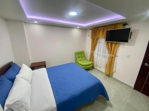 um quarto com uma cama azul e uma cadeira verde em Hotel Dubai Suite em Pasto