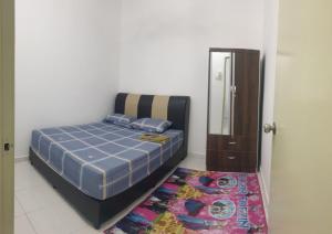 a bedroom with a bed and a mirror and a rug at HOMESTAY IMPIAN QASEH MANJUNG (MUSLIM) in Seri Manjung