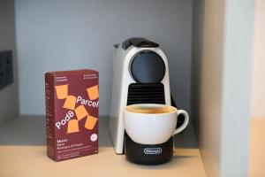 Beach Road Hotel في سيدني: آلة صنع القهوة وكوب من القهوة على طاولة