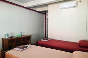 a bedroom with two beds and a red couch at Omah Pitoe Yogya Homestay in Yogyakarta