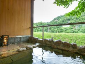 ein Wasserpool neben einem Haus in der Unterkunft Takanosukan in Sekikawa