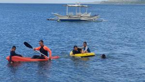 a group of people in kayaks in the water with a boat at Shenanigans Glamping Resort in Zamboanguita