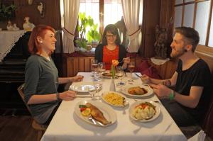 Un gruppo di persone seduti intorno a un tavolo che mangiano cibo di Gasthof und Pension zum Kreuz a Lautenbach